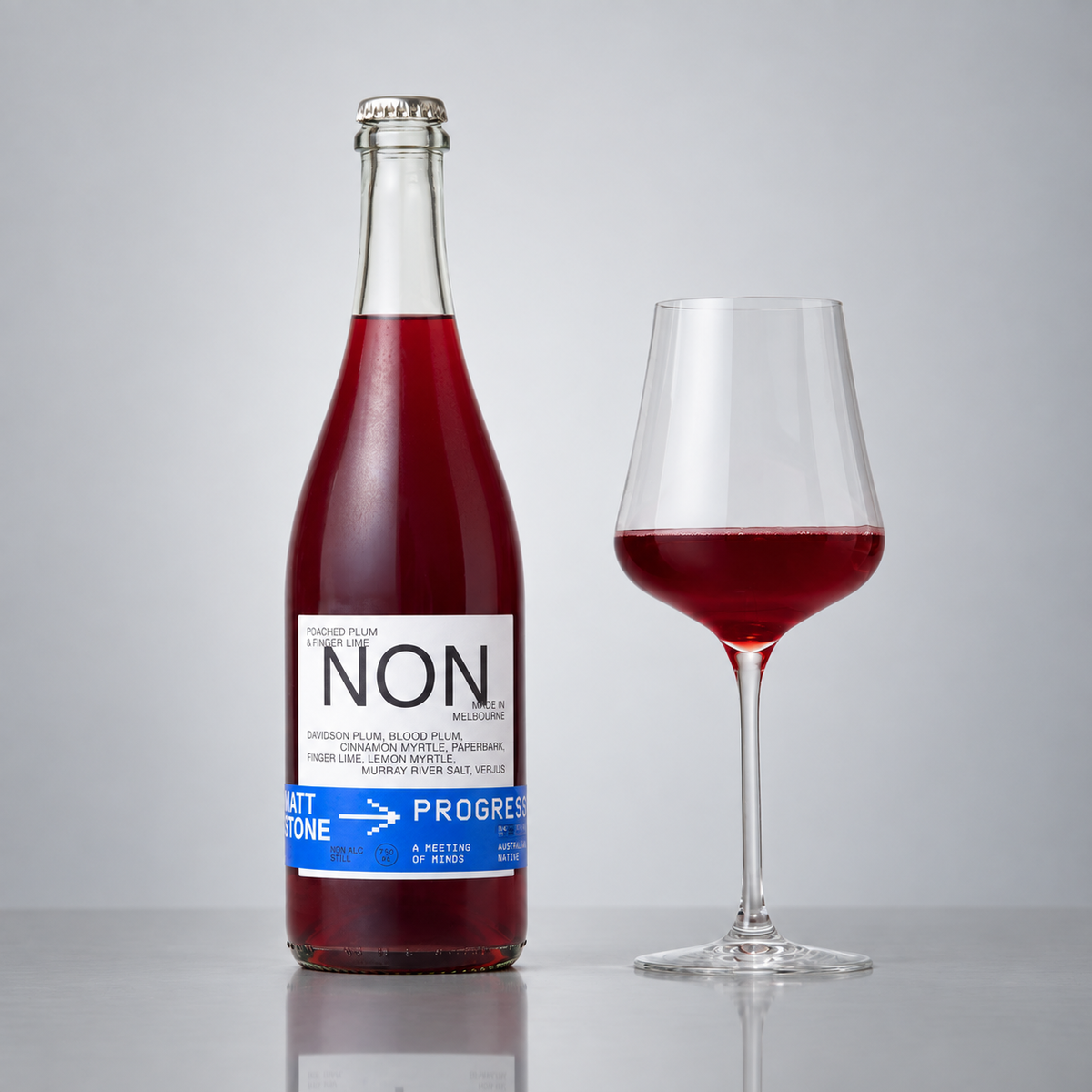 PROGRESS1 Poached Plum and Finger Lime bottle and filled wine glass on a grey background